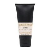 Black tube of amber hand cream on a white background